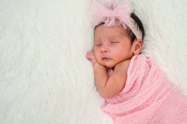 newborn baby girl sleeping in cloth wrap blanket on a bed