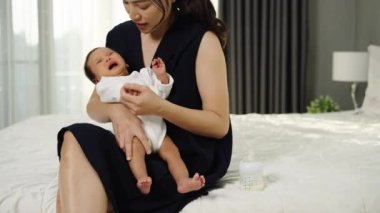 Anne kucağında ve teselli ediyor ağlayan yeni doğmuş bebeğini kollarında bir yatakta.