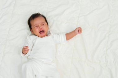 newborn baby lying and crying on a bed