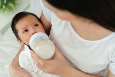 Anne yeni doğmuş bebeğini yatakta emziriyor.