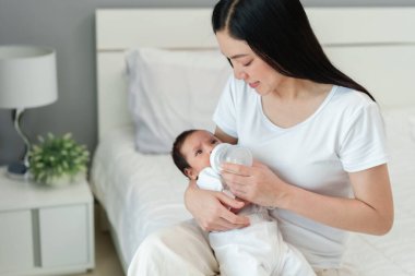 Anne yeni doğmuş bebeğini yatakta emziriyor.