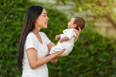 mother holding and playing with her baby newborn in the garden