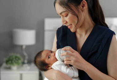 Anne yeni doğmuş bebeğini yatakta emziriyor.