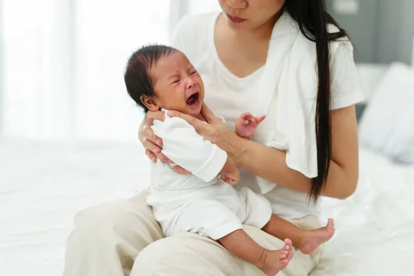 stock image mother holding burping and crying baby in a bedroom after feeding milk