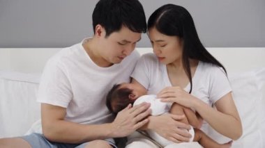 parent (mother and father) trying to consoling crying baby on a bed