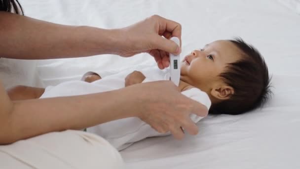 母亲在床上测量新生儿腋窝温度 — 图库视频影像