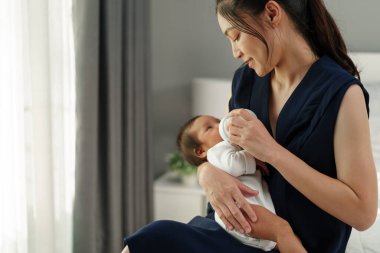 Anne yeni doğmuş bebeğini yatakta emziriyor.