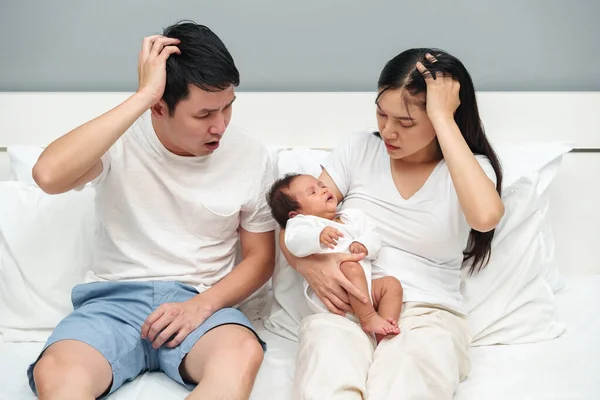 stressed family (father and mother and baby) on a bed