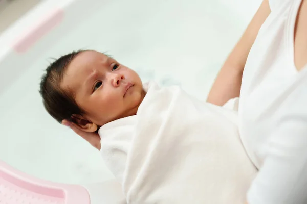 mother prepare to give a bath and wash newborn baby hair in a bathtub