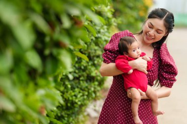mother holding and playing with her baby newborn in the garden