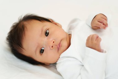 newborn baby lying on a white bed