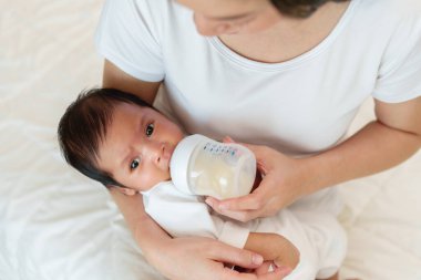 Anne yeni doğmuş bebeğini yatakta emziriyor.