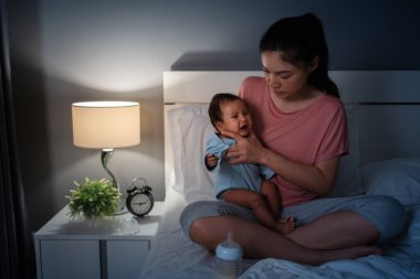 Anne gece yatakta süt içtikten sonra geğirerek ve ağlayarak bebek besliyor.