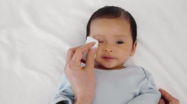 Anne, yeni doğmuş bebek yüzünü pamuklu bezle temizleyip siliyor.