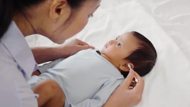 Mutter Reinigt Mit Wattestäbchen Ohr Von Neugeborenem Auf Bett — Stockvideo