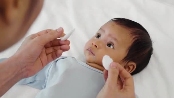 Мать Чистит Вытирает Глаза Новорожденному Помощью Ваты Кровати — стоковое видео