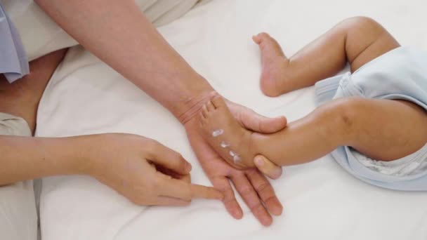 母亲在新生儿脚部涂润肤霜 — 图库视频影像