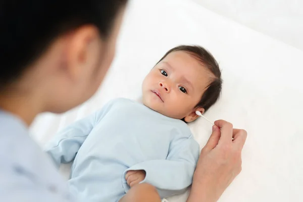 Mutter Reinigt Mit Wattestäbchen Ohr Von Neugeborenem Auf Bett — Stockfoto