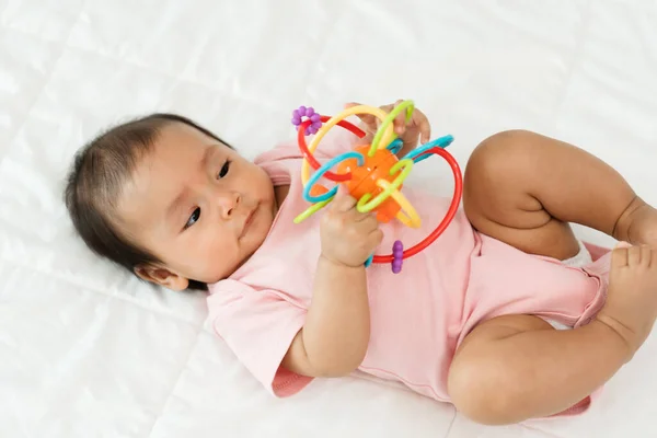赤ちゃんはカラフルなゴム製のおもちゃをベッドで — ストック写真