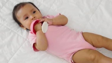 Bebek mantar ısırıyor, plastik oyuncağı yatağa bağlıyor.