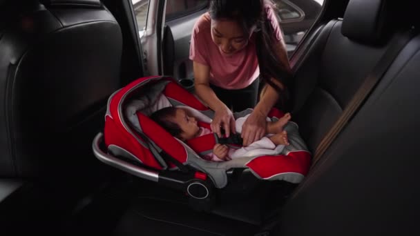 母は安全ベルトをほどいて車のシートから赤ん坊を取り出し — ストック動画