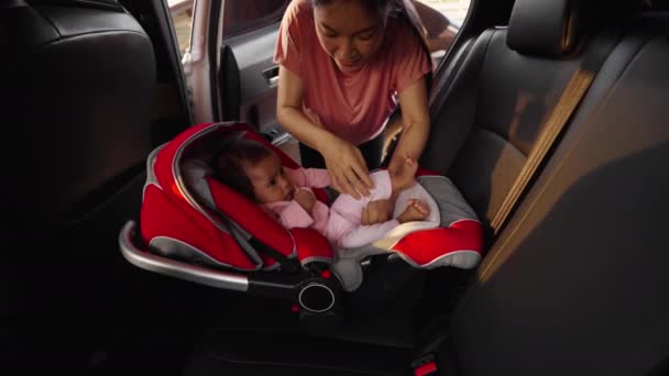 幼い赤ちゃんを車のシートに乗せて安全ベルトを締め — ストック動画