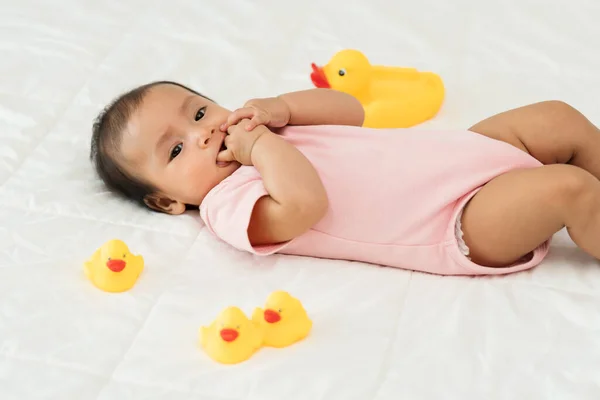 아기가 침대에서 손가락빨기 노란색 장난감으로 — 스톡 사진