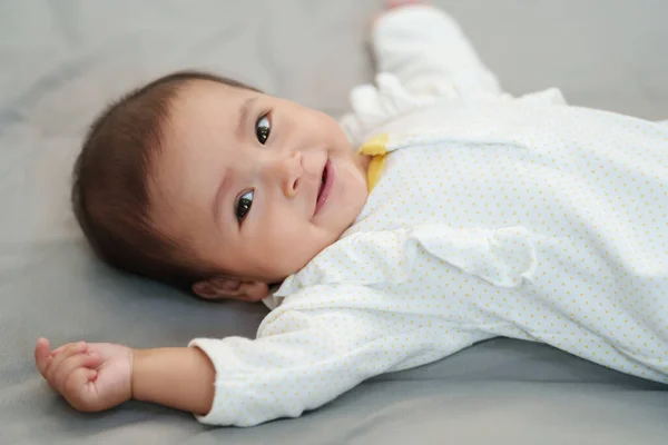 ベッドの上に寝そべっている間の幸せな赤ちゃんの笑顔 — ストック写真