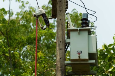 Elektrikçi, yalıtkan üzerindeki sigorta prizini onarmak için klemp çubuğu kullanıyor. Yüksek voltajlı elektrik direğini destekliyor..