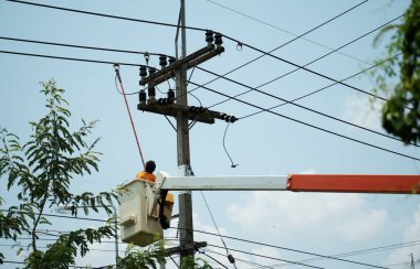 Elektrikçi elektrik direğindeki gücü geri getirmek için klemp çubuğu (yalıtımlı araç) kullanıyor