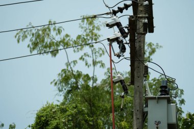 Elektrikçi, yalıtkan üzerindeki sigorta prizini onarmak için klemp çubuğu kullanıyor. Yüksek voltajlı elektrik direğini destekliyor..