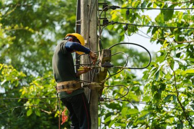 Teknisyen elektrik direklerine tırmanıyor ve kabloları bağlıyor.