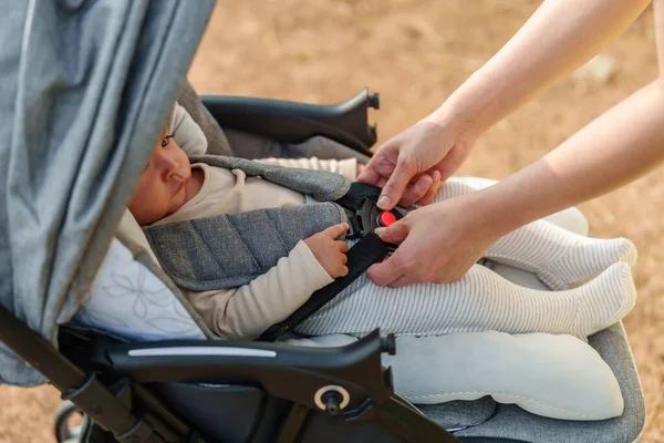 stock image woman fastening belt on the stroller with baby