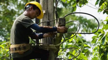 20 Mayıs 2023: NAKHON RATCHASIMA - THAILAND: teknisyen elektrik direklerine tırmanıyor ve kabloları bağlıyor