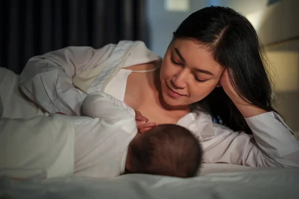 어머니는 침대에서 아기에게 모유를 먹이고 로열티 프리 스톡 사진