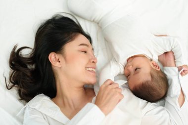 Mutlu anne yatar ve bebek bebekle bir yatakta oynar (üst manzara))