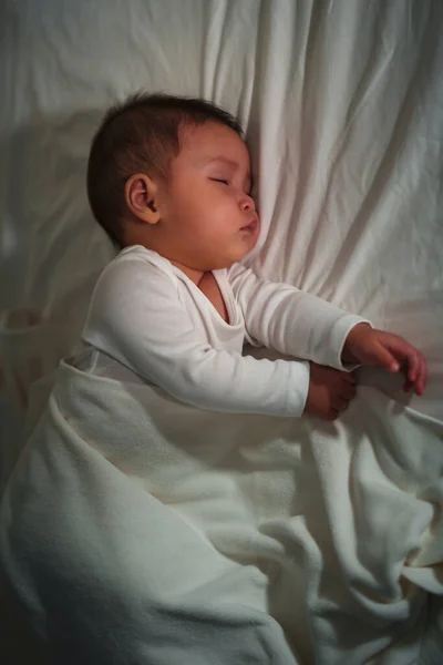 infant baby sleeping on a bed at night