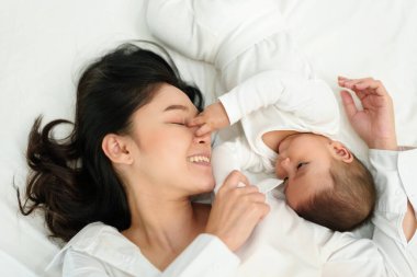 Mutlu anne yatar ve bebek bebekle bir yatakta oynar (üst manzara))