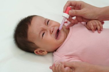 Hasta bebek ağlayarak bir damlacıkla sıvı ilaç yemeyi reddediyor.