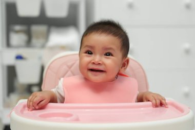Evdeki yemek sandalyesinde oturan mutlu bir bebek. yemek zamanı