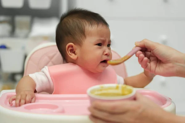 泣いている乳児にスプーンで食事を与え食事を拒否し — ストック写真