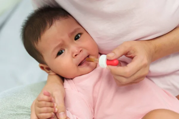 stock image mother feeding a liquid medicine to sick infant baby with a dropper