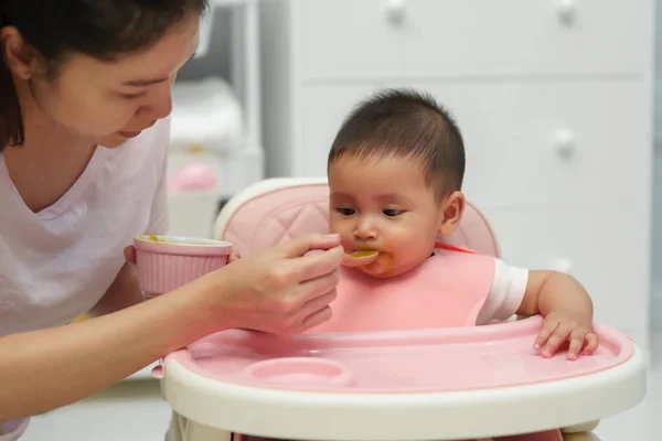 母親は乳児に食べ物を与えスプーンで家で食事をし — ストック写真