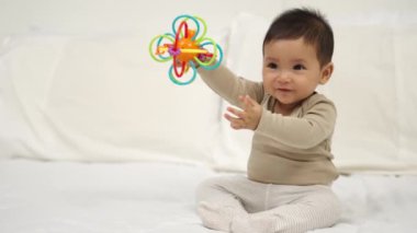 Bebek renkli lastik ısırıklarıyla oynuyor. Oyuncak yatakta.