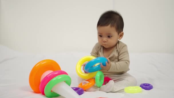 Baby Spielt Pyramidenspielzeug Mit Farbigen Ringen Auf Einem Bett — Stockvideo