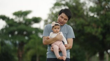 father holding and talking with infant baby in the park