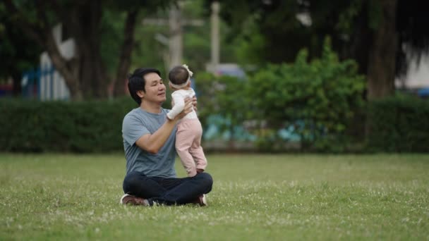 Father Holding Lifting His Infant Baby While Sitting Grass Field — Stockvideo