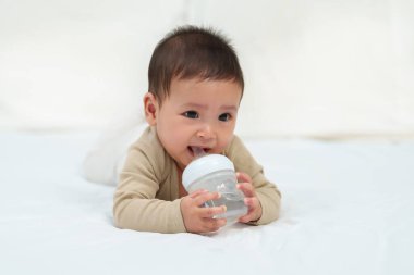 Bebek bir yatakta şişeden su içiyor