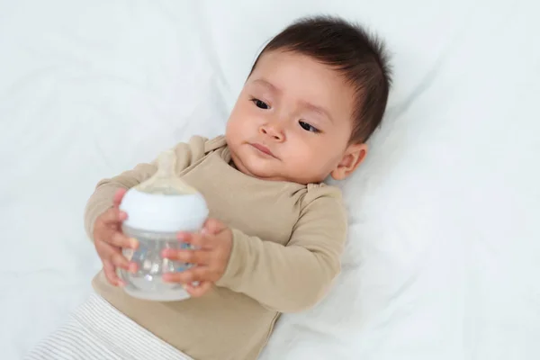 Baby Trinkt Wasser Aus Flasche Auf Einem Bett — Stockfoto