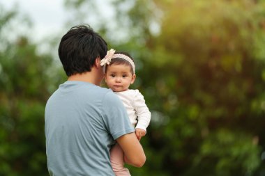 Baba parkta bebeği tutuyor.